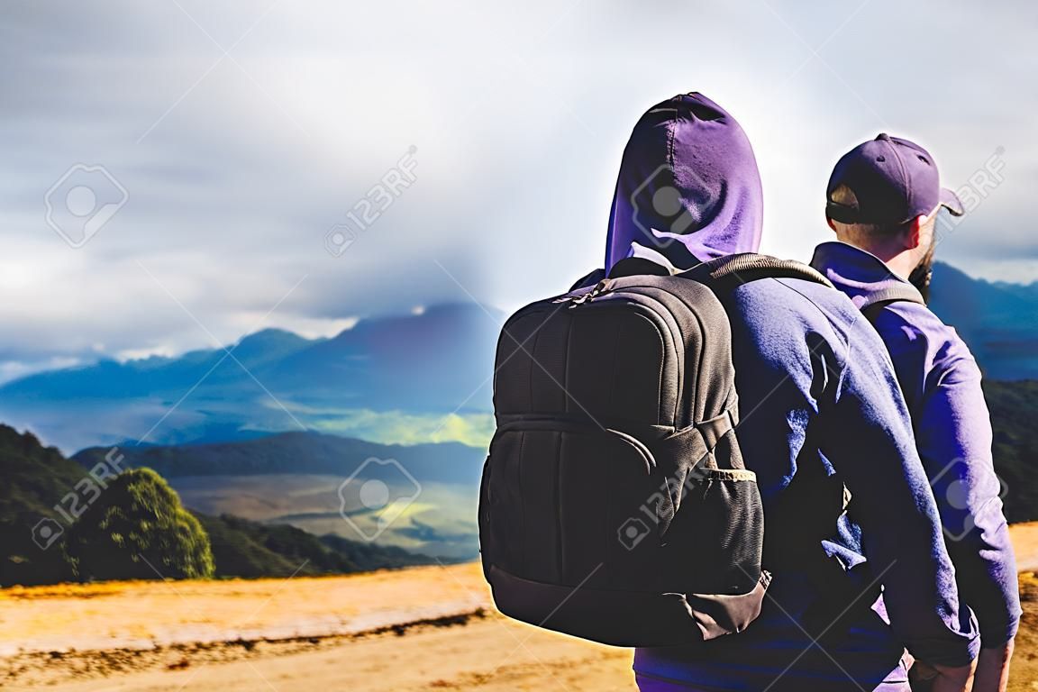 tourist traveler with black backpack on background top mountain, traveler look at blue sky clouds, hiker enjoying nature panoramic landscape in trip, relax holiday mockup concept in trekking trip