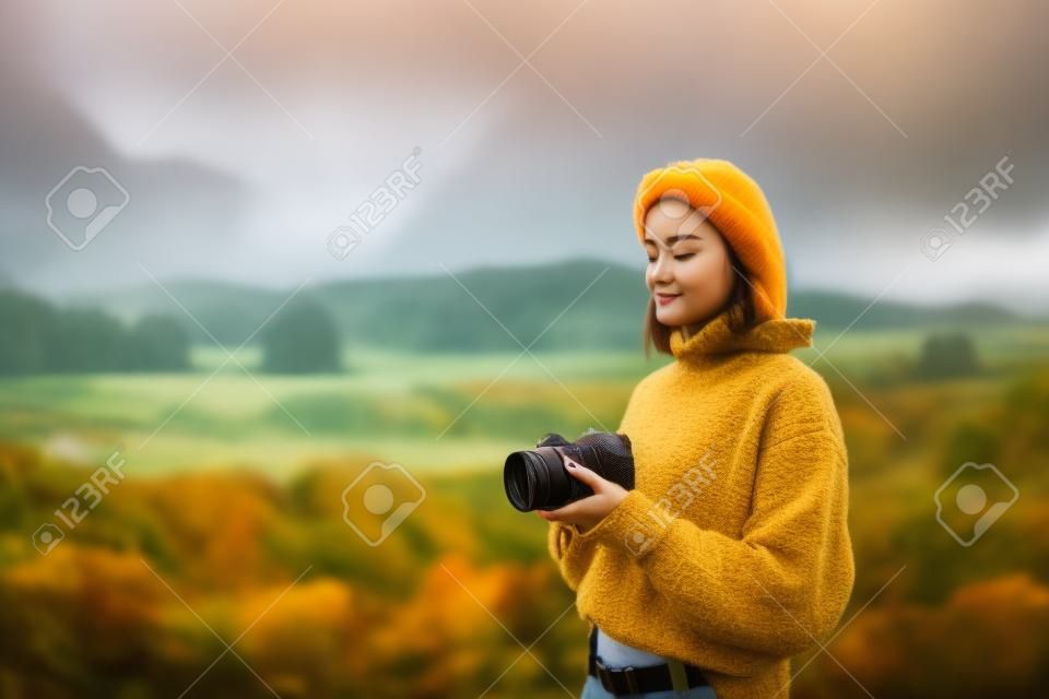 사진작가 소녀는 배경 가을 개구리 산에서 카메라로 사진을 찍고, 관광객은 자연 안개 풍경, 취미 개념, 복사 공간을 즐깁니다.
