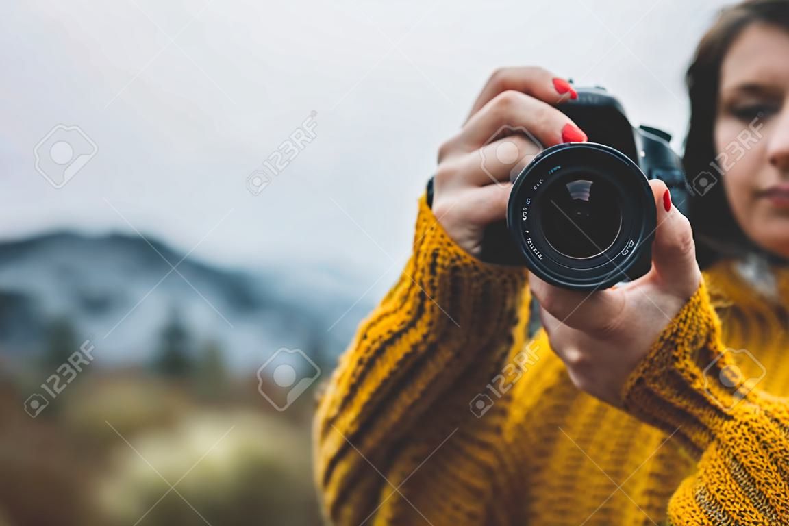 photographer girl hold in hands video camera take photo on background autumn foggy mountain, tourist shooting nature mist landscape, photo lens closeup