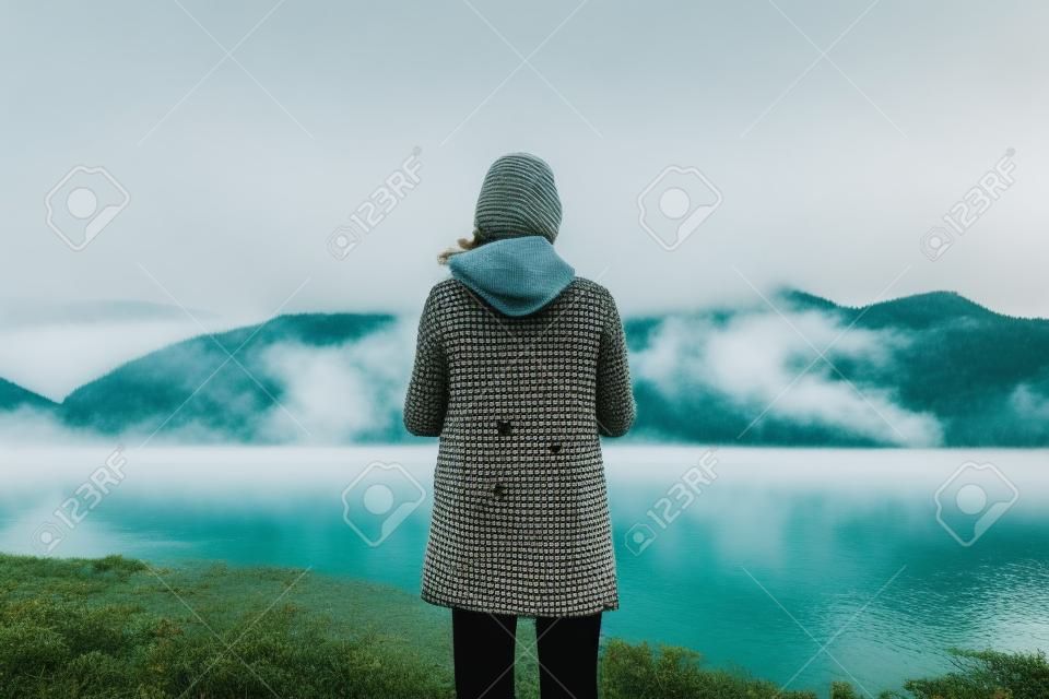hipster tourist relax on foggy lake, mist mountain nature, traveler girl enjoy breathing of fresh clean air in trip in spain, vacation concept