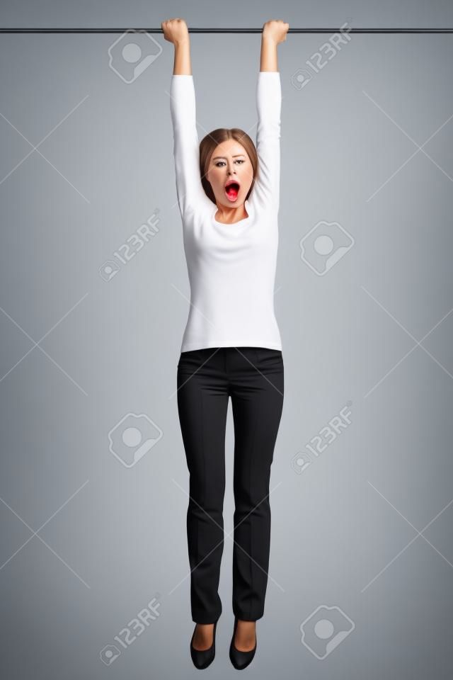 woman hanging with hands on a pole or bar. Funny image of shocked looking female model isolated on white background.