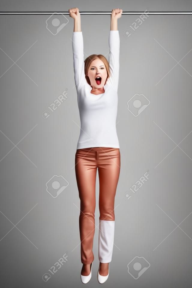woman hanging with hands on a pole or bar. Funny image of shocked looking female model isolated on white background.
