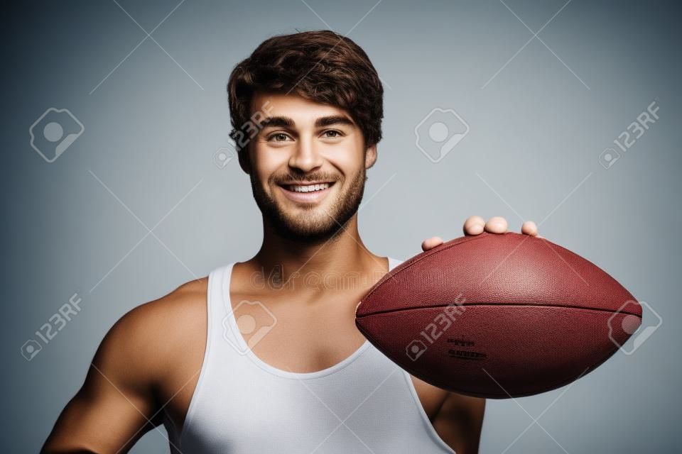 American football - casual man showing american football isolated on white background. Young male sport fitness model isolated on white background. Focus on football.