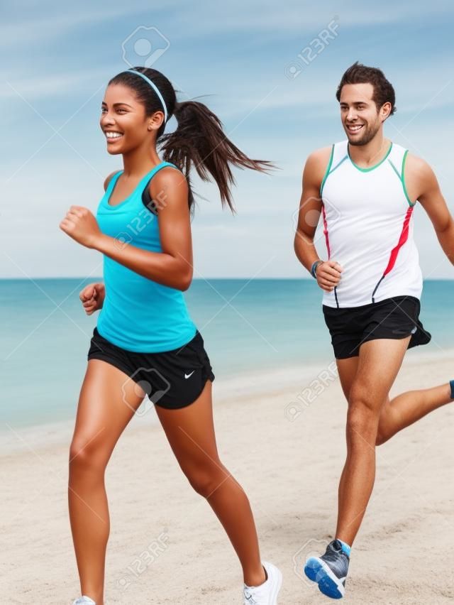 Les gens qui hébergent: les coureurs en couple à l'extérieur de formation sur la plage. Jeune modèle multiracial de fitness femme et l'homme caucasien coureur.