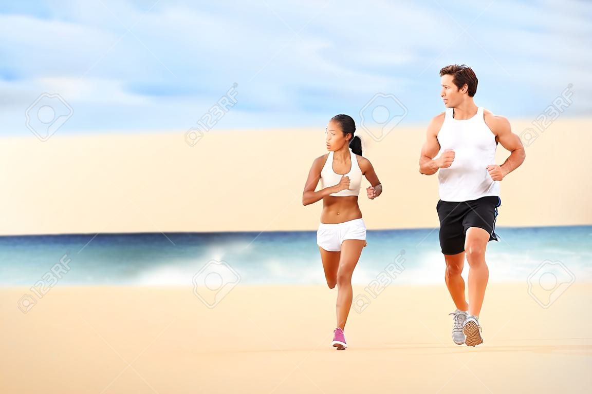 Running people. Runners couple on beach run jogging training. Fit man athlete and woman fitness runner working out together running and talking having fun on beautiful beach. Multiracial couple.