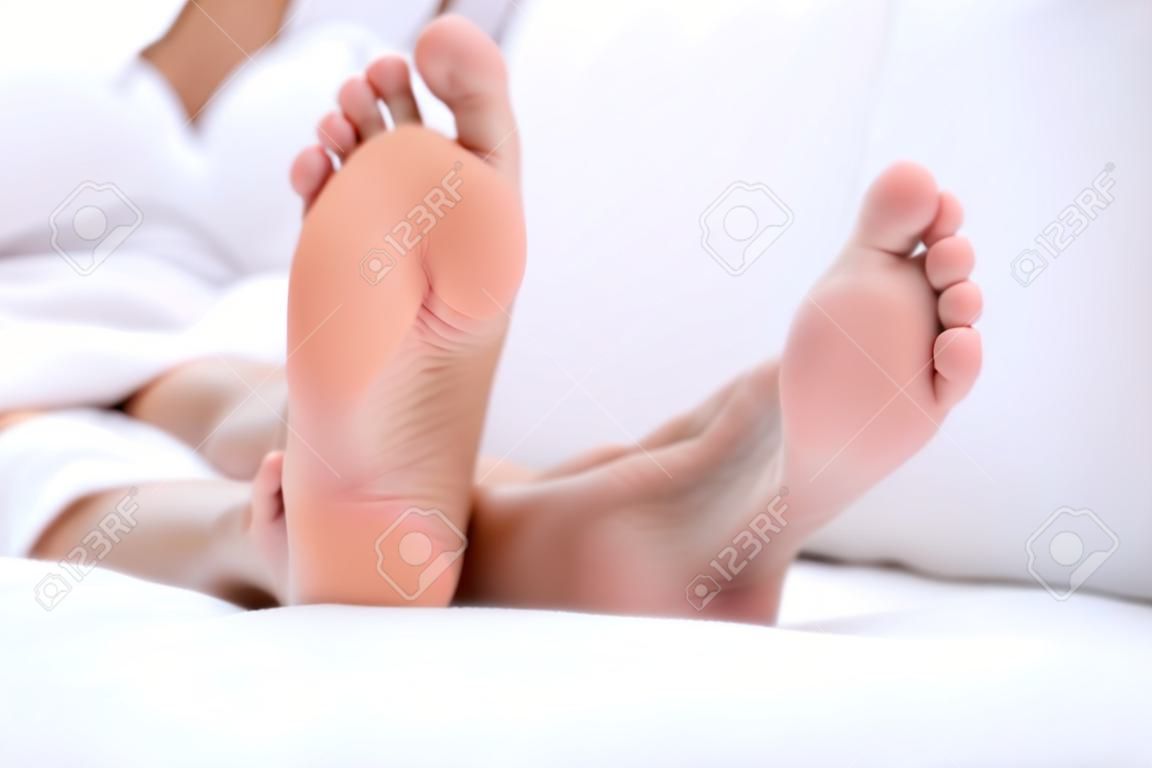 Pies de mujer closeup - descalzo mujer de relax en el sofá. Cierre de los pies femeninos de la mujer hermosa joven que se sienta en el sofá afuera.