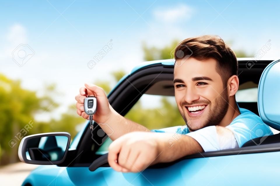 새로운 자동차 키를 게재하는 렌터카를 운전하는 남자. 젊은 성인 자동차 임대 또는 임대 또는 구입에 대 한 키와도 여행에 흥분.