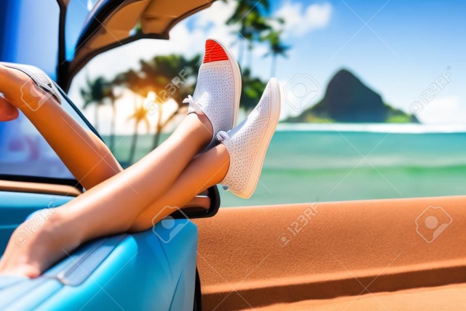 Erholsamen Urlaub Auto road trip mit den Füßen im Fenster. Cabrio Urlaubskonzept mit weiblichen Beine vor Oahu orientierungspunkt: Chinamans Hat in Hawaii, USA.
