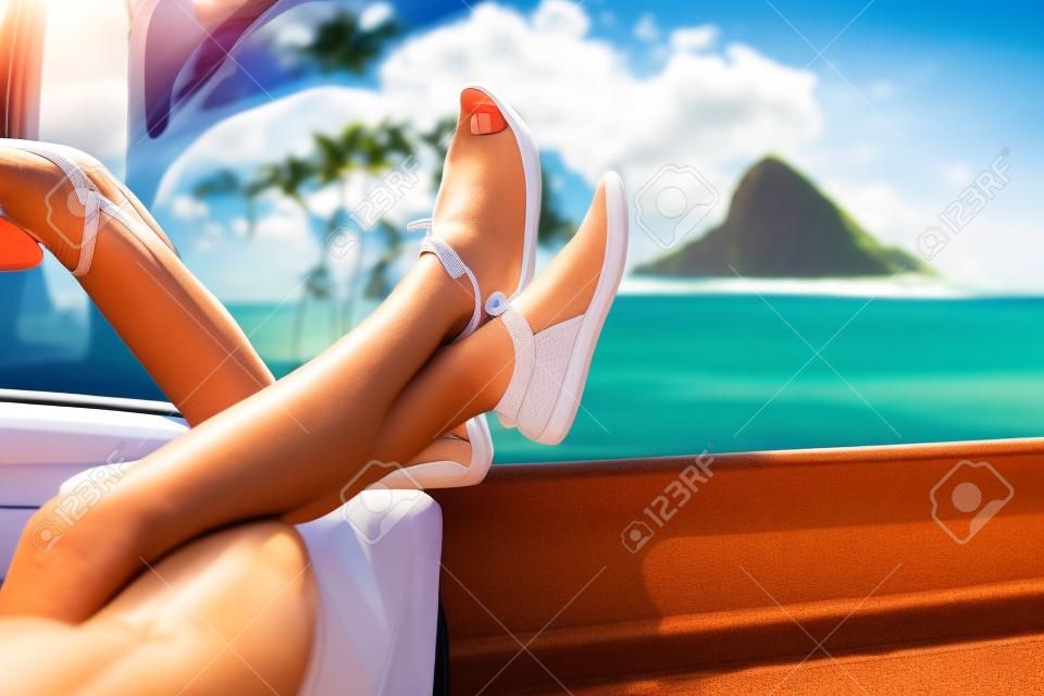 Rilassante vacanza auto da strada viaggio con i piedi alla finestra. Convertible concetto di vacanza auto con gambe femminili davanti a Oahu punto di riferimento: Cappello Chinaman nelle Hawaii, Stati Uniti d'America.