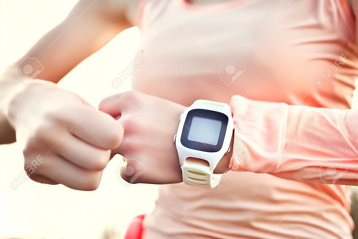 心臟監測儀的智能手錶運動。運動員穿心臟監測儀。亞軍利用體育的SmartWatch在外面跑的鍛煉。使用可穿戴技術的女運動員的跟踪活動。