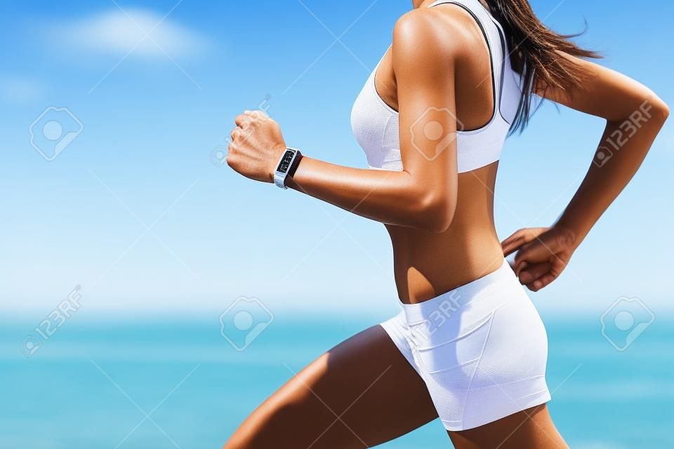 technologie Wearable montre intelligente gros plan, femme active porter l'activité bracelet de suivi sur le poignet. Runner fille courir vite intense en plein air de courir sur la plage océan fond vivre une vie saine. Jambes gros plan.