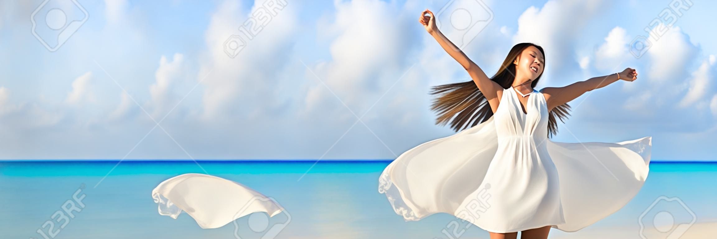 Свобода молодая женщина с оружием, вытянутой в небо с голубой океан ландшафта пляж фон копирования пространство. Баннер панорамы. Азиатская девушка в белом платье, танцы беззаботный в закат.