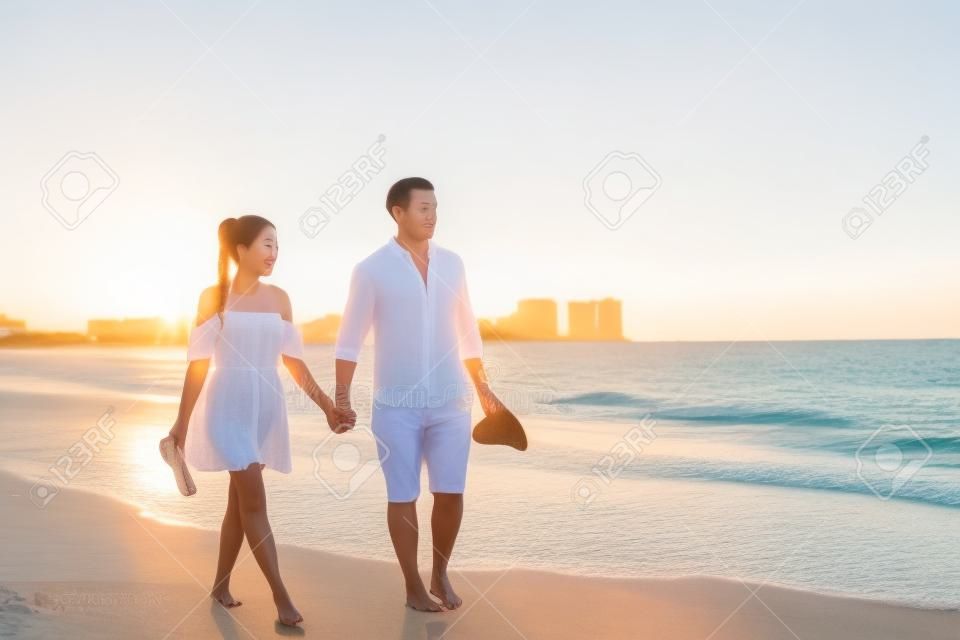 해변 커플 낭만적인 일몰 산책 아시아 여자와 백인 남자 플로리다 휴가 해변 여행 휴가 흰색 드레스와 리넨 옷을 입고 산책 편안한 산책. 행복한 인종 간 관계.
