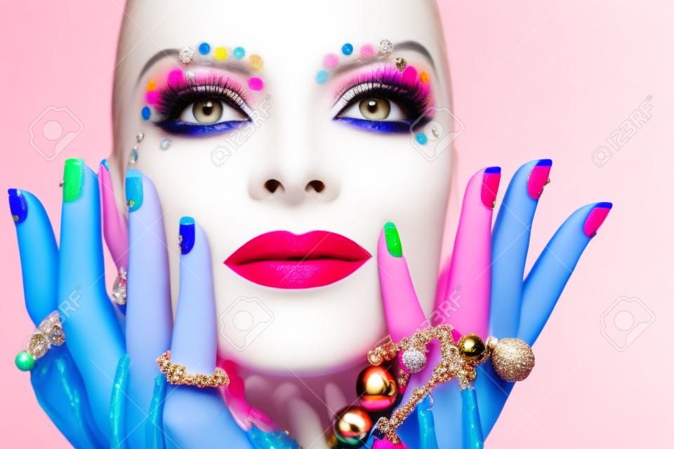 Kolorowy makijaż i manicure z ozdobami o różnych kształtach i kolorach na blondynka.