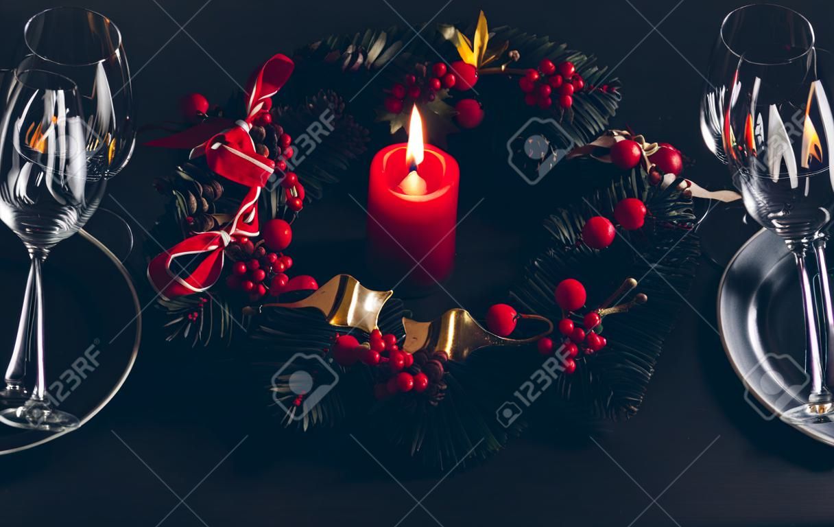 Beautiful Christmas dinner place setting for two. Table decorated with a wreath and a candle.
