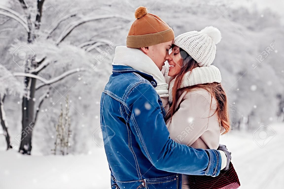 Date de la Saint-Valentin. Jeune couple d'amoureux élégant marchant dans le parc d'hiver. Homme et femme étreignant appréciant le paysage enneigé à l'extérieur