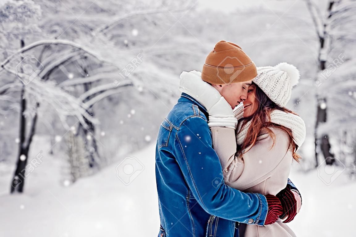 Date de la Saint-Valentin. Jeune couple d'amoureux élégant marchant dans le parc d'hiver. Homme et femme étreignant appréciant le paysage enneigé à l'extérieur
