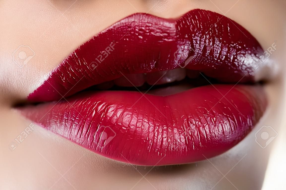 Close-up of woman's lips with fashion red make-up. Beautiful female mouth, full lips with perfect makeup. Classic visage. Part of female face. Macro shot of beautiful make up on full lips.