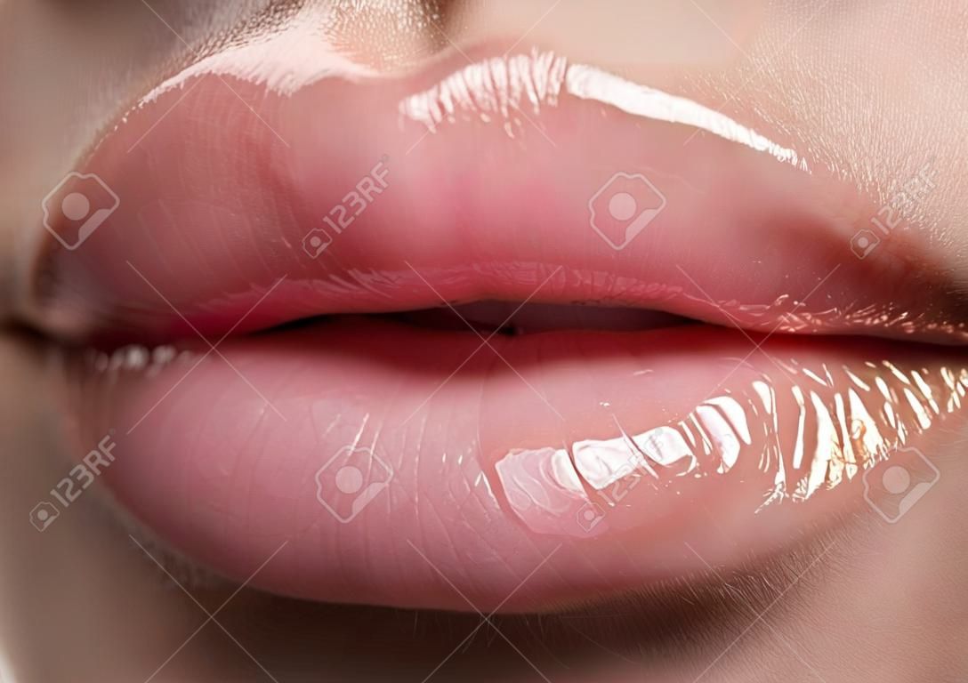 Close-up belle labbra femminili con il trucco luminoso lipgloss. Perfetto pelle pulita, luce labbro nuovo make-up. Bella spa macro girato con tenera rosa lip gloss. Spa e cosmetici