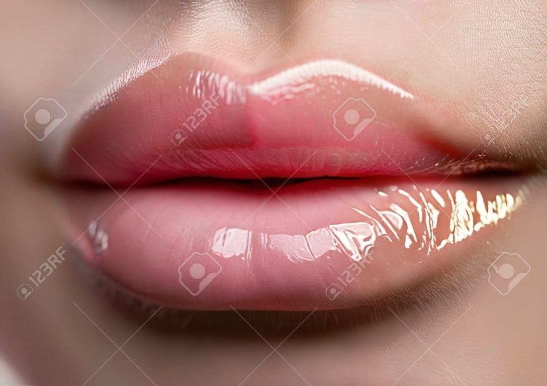 Close-up belle labbra femminili con il trucco luminoso lipgloss. Perfetto pelle pulita, luce labbro nuovo make-up. Bella spa macro girato con tenera rosa lip gloss. Spa e cosmetici
