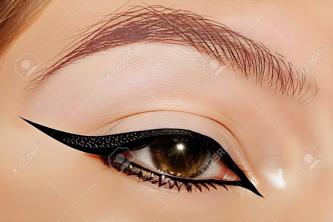 Piękne makro kobiece oko z moda czarny eyeliner makijaż. idealny kształt graficznej podszewki, styl minimalizmu. kosmetyki i makijaż. zbliżenie makro oczu mody liniowej wizaż