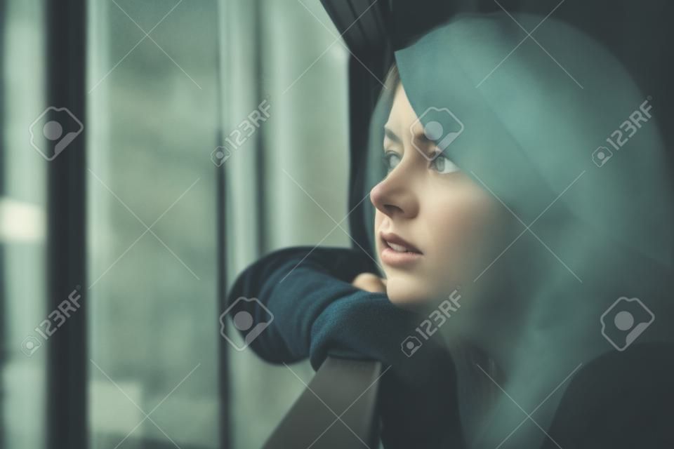 Młoda smutna kobieta patrząca na zewnątrz przez balkon budynku mieszkalnego