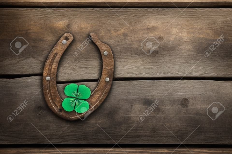 Ferradura velha e trevo de quatro folhas em uma placa de madeira vintage. O conceito de sorte, sorte, sorte. Cartão do dia de St. Patricks.