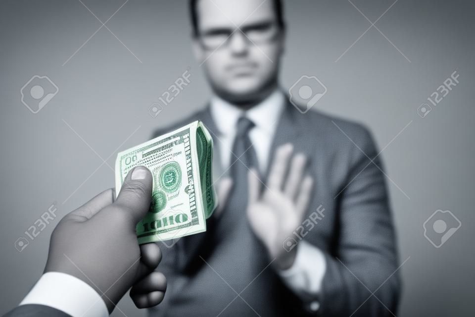 The businessman refuses US dollars in the studio on a gray background. The concept of corruption. One hundred dollar bills. The concept against corruption in business activities, against bribery.