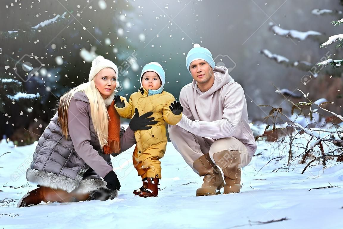 Happy family Dad, mom and baby sy on a winter walk in the forest. Concept for christmas, family, relatives, vacations, fresh air