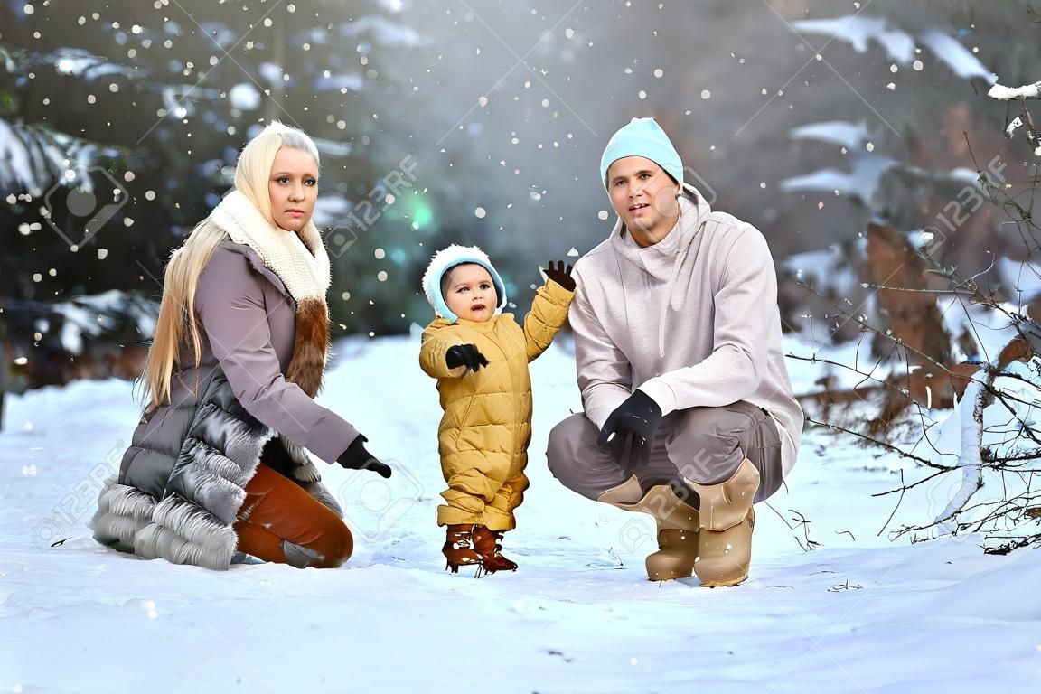 Happy family Dad, mom and baby sy on a winter walk in the forest. Concept for christmas, family, relatives, vacations, fresh air