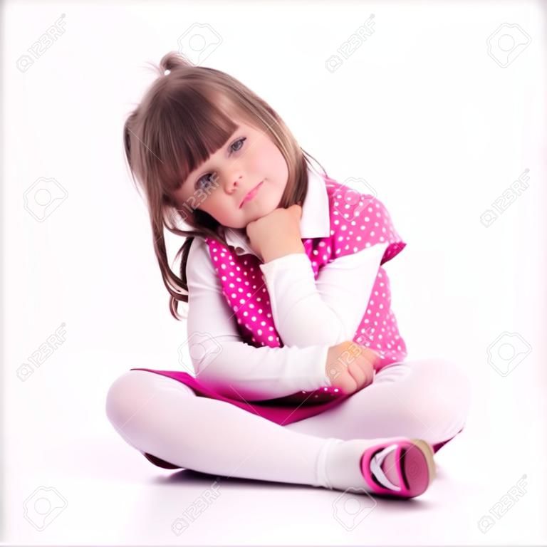 Little girl preschooler model in pink skirt, sandals and dotted shirt and sitting on the floor with mobile phone