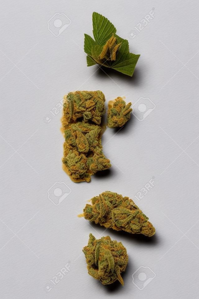 Flora de cannabis, desmoronar, estilhaçar o concentrado no fundo branco. A maconha se concentra.