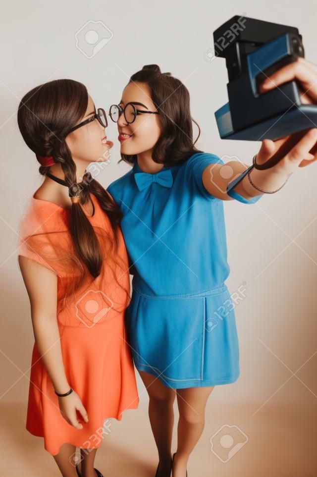 Young nerdy girls taking a selfie with instant camera  studio shot 
