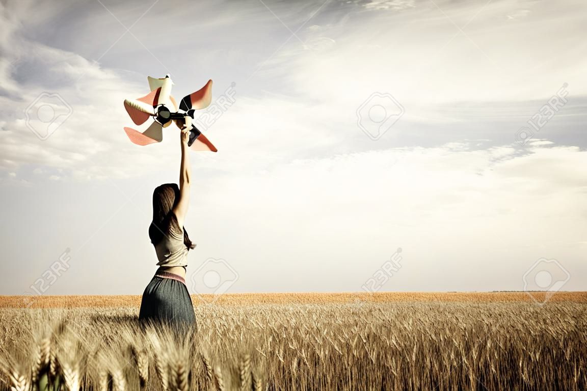 Girl with wind turbine at wheat field
