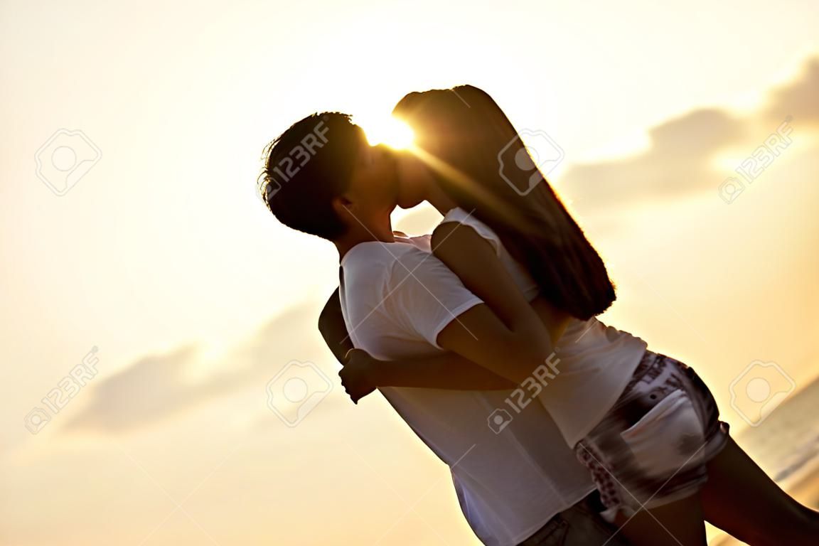Casal beijando no nascer do sol na praia.