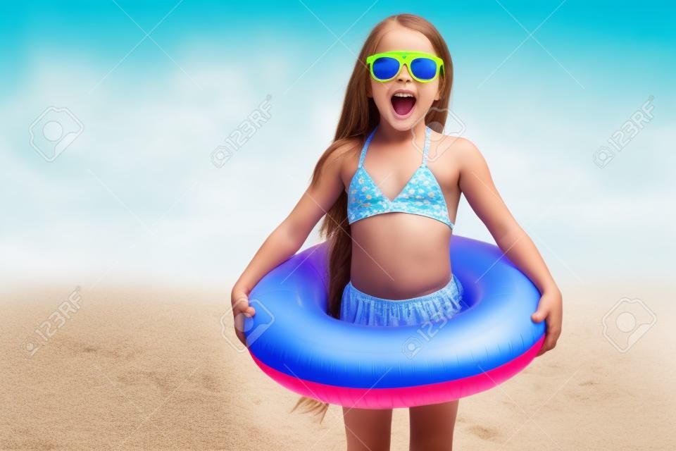 child with sunglasses and inflatable ring at the beach
