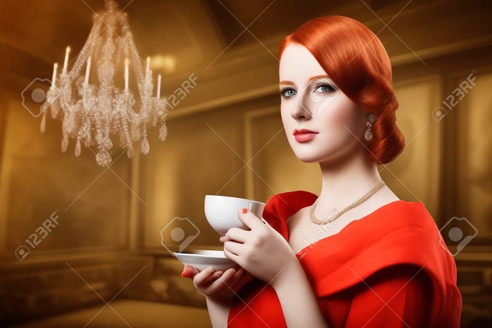 美麗的紅發女子與一杯茶。照片中的舊顏色的影像風格。