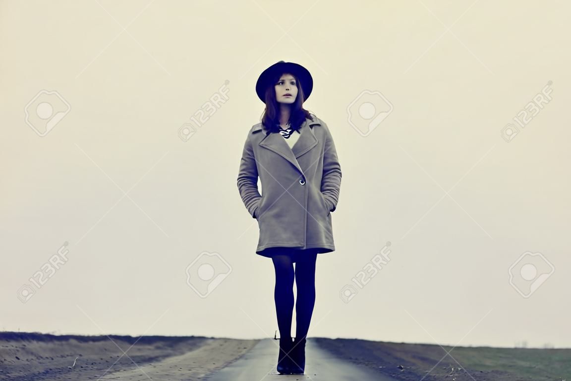 portrait of a young beautiful woman with suitcase standing on the road