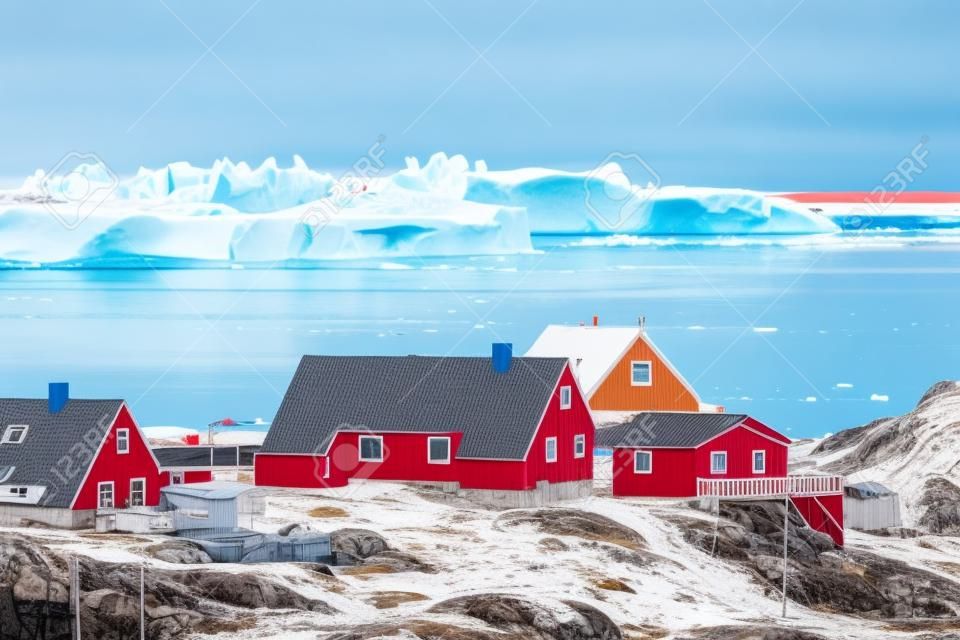 Aerial View of Arctic city of Ilulissat, Greenland. Colorful houses in the center of the town with icebergs in the background in summer on a sunny day with blue sky and clouds