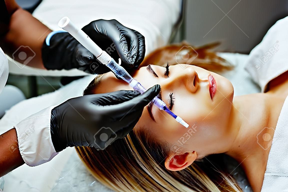 Portret van vrouwelijke patiënt met moderne niet-invasieve procedure van neuscorrectie, Dokter injecteert stof in patiënt neus, esthetische correctieve behandelingen concept