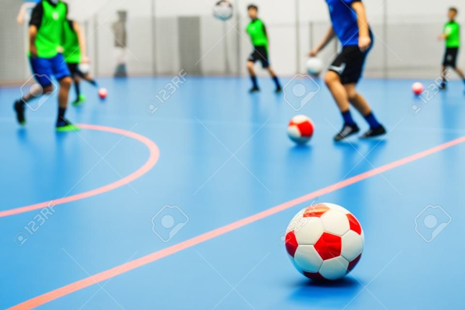 フットサルトレーニングをしている屋内フットサルサッカー選手。屋内サッカースポーツホール。フットサル選手がボールを蹴る。フットサルトレーニングドリブルドリル。スポーツの背景。インドアサッカーリーグ