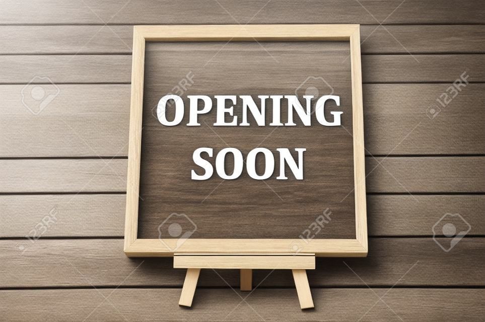 Opening soon text engraved on wooden frame. Business opening concept.