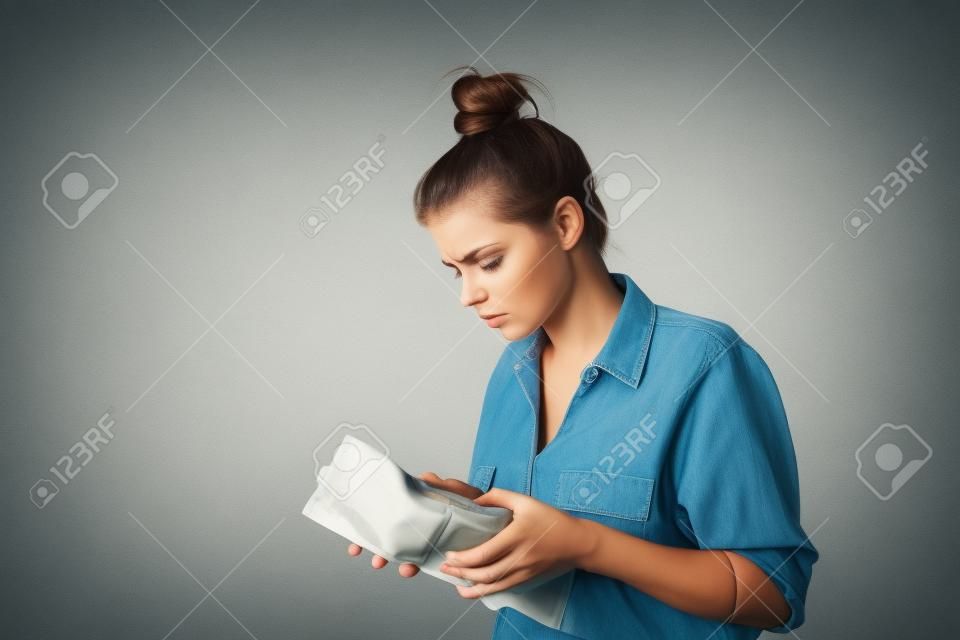 Worried slim woman is looking at an empty wallet
