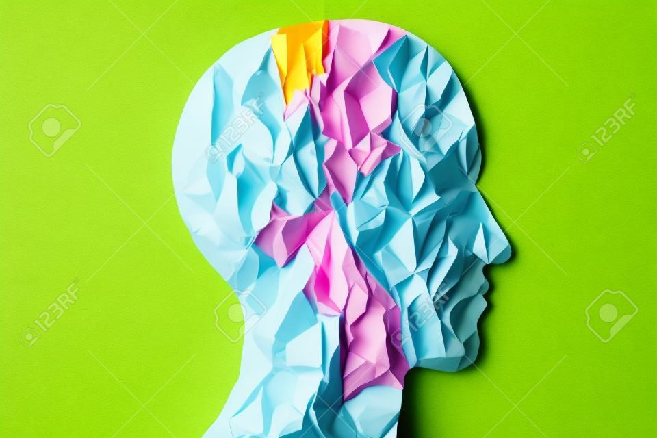 Sylwetka głowy wykonana ze zmiętego różowego papieru w kształcie ludzkiej głowy z miejscem na kopię na minimalnej koncepcji zielonego i żółtego papieru