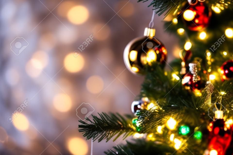 Nahaufnahme von Dekorationen hängen von den Zweigen eines Weihnachtsbaums in einer Heimat mit Menschen im Hintergrund