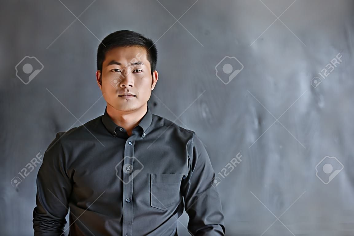 Confident Asian businessman standing in front of a blank chalkboard
