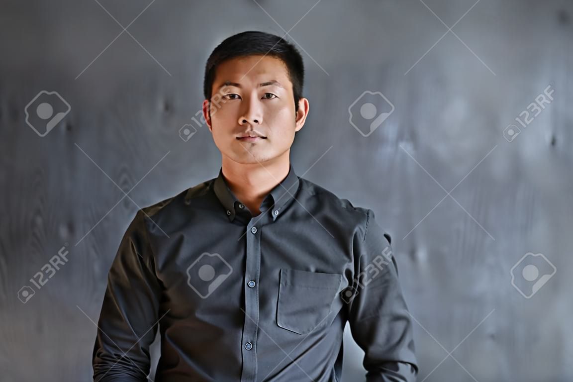 Confident Asian businessman standing in front of a blank chalkboard