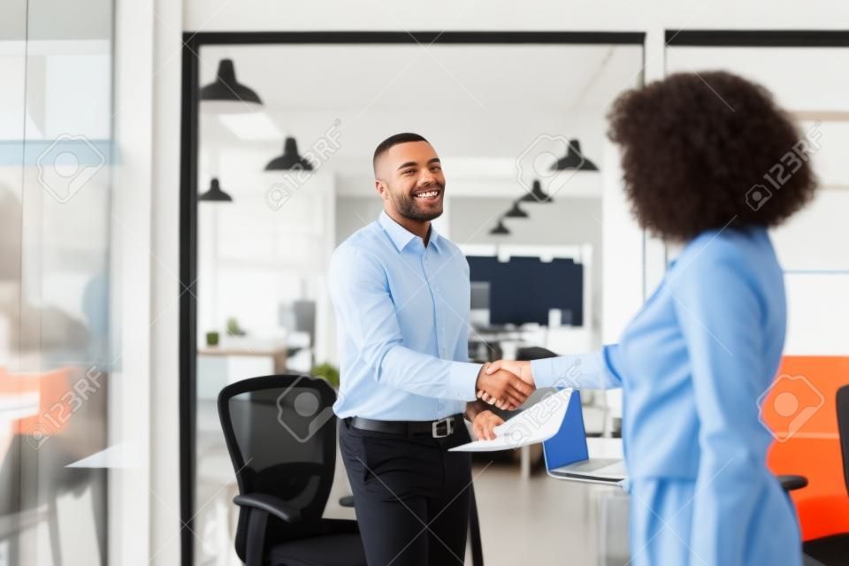 Uśmiechnięty menedżer wita nowego pracownika w biurze