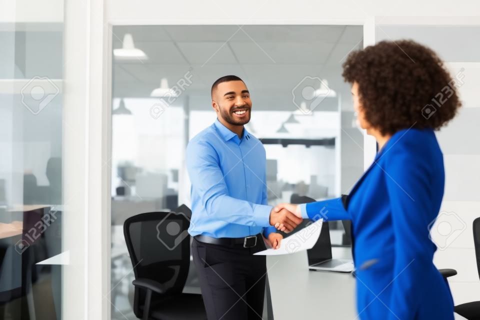 Uśmiechnięty menedżer wita nowego pracownika w biurze