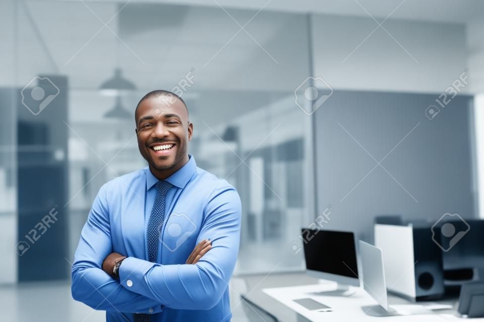 Smiling African American businessman standing alone in a large office